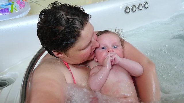 Slow motion shot of a beautiful woman with her baby boy is relaxing in hot tub