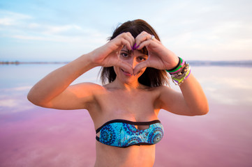 Pretty woman in a colorful lake making a heart with her hands