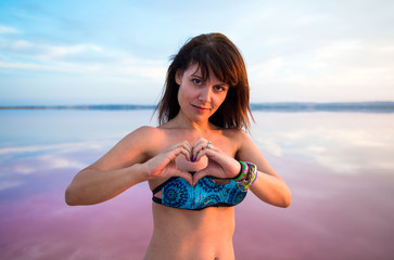 Pretty woman in a colorful lake making a heart with her hands