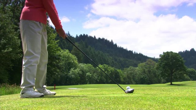 Golfer addressing ball, swinging club, and watching ball sail down the fairway