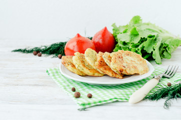 
vegetable breakfast or lunch , zucchini pancakes with dill , fresh tomatoes , lettuce and herbs on a wooden background