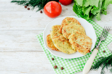 
vegetable breakfast or lunch , zucchini pancakes with dill , fresh tomatoes , lettuce and herbs on a wooden background