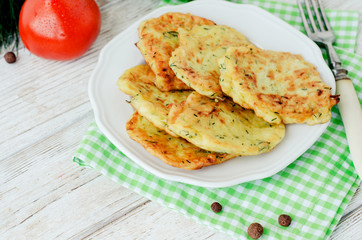 
vegetable breakfast or lunch , zucchini pancakes with dill , fresh tomatoes , lettuce and herbs on a wooden background