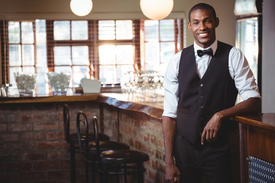 Portrait of bartender standing at bar counter