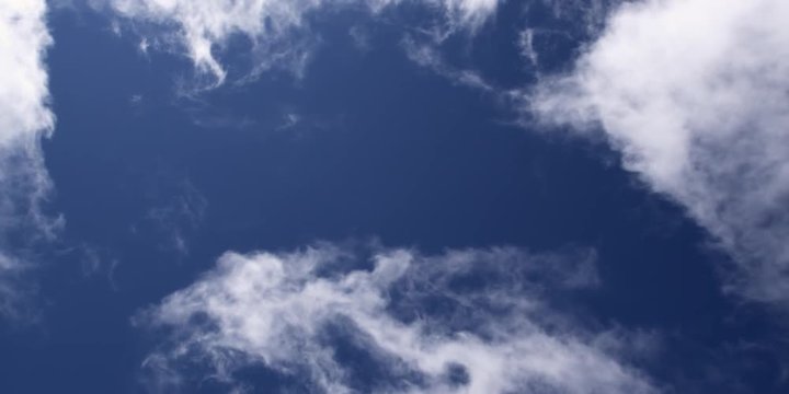Time-lapse wispy white clouds swirling in blue sky