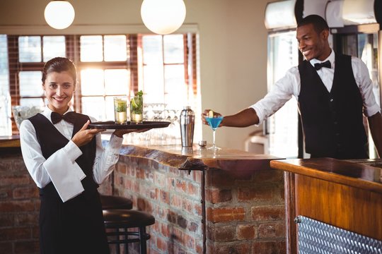 Female bartender holding a serving tray with two cocktail glass