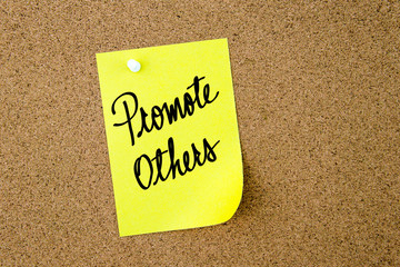 Promote Others written on yellow paper note