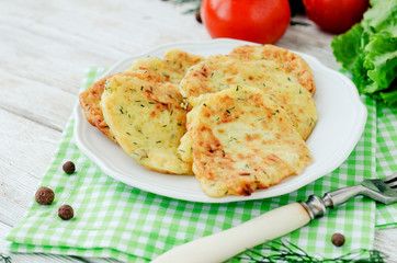 
vegetable breakfast or lunch , zucchini pancakes with dill , fresh tomatoes , lettuce and herbs on a wooden background