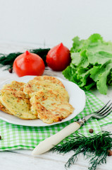 
vegetable breakfast or lunch , zucchini pancakes with dill , fresh tomatoes , lettuce and herbs on a wooden background