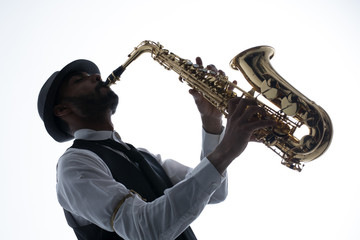 Saxofonista en contrapicado sobre fondo blanco