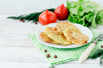 
vegetable breakfast or lunch , zucchini pancakes with dill , fresh tomatoes , lettuce and herbs on a wooden background