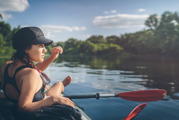 Summer vacation - Back view of young woman kayaking on river.