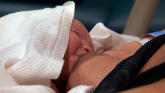 Close-up face of newborn nursing at his mother's breast