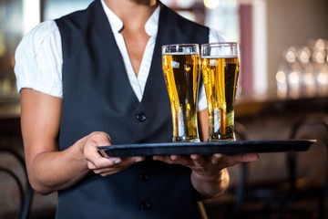 Waitress holding serving tray with two glass of beer