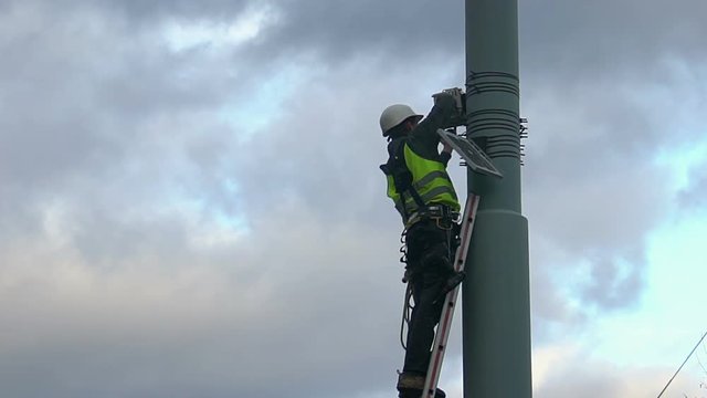 Maintenance worker servicing street video surveillance system, work at height