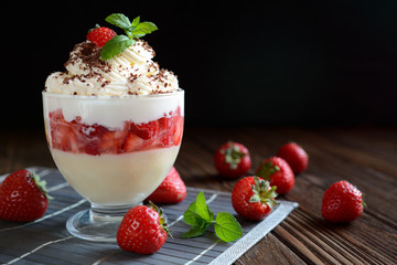 Vanilla pudding with strawberries, mascarpone and whipped cream on black background
