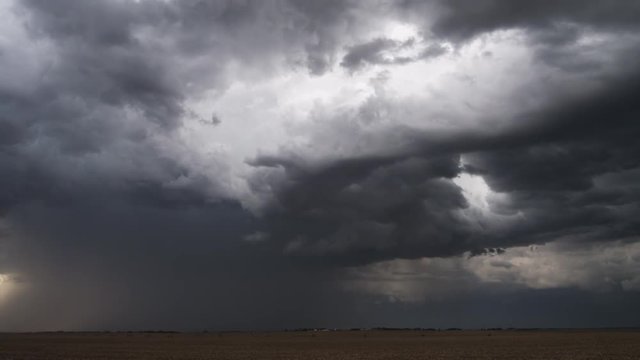 Dark gray time-lapse clouds move toward the horizon beyond a wheatfield