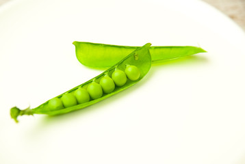 Green pea pod on the  big white plate.