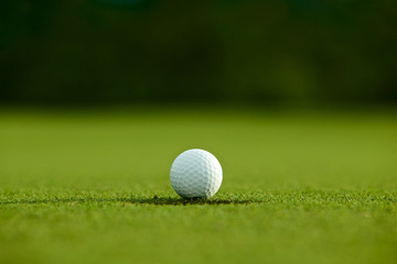 selective focus. white golf ball near hole on green grass good f