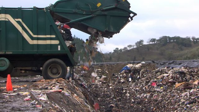 Garbage truck unloading into landfill