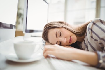 Obraz na płótnie Canvas Tired businesswoman taking nap in creative office