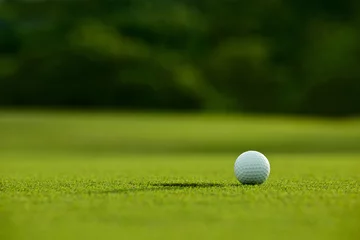 Rolgordijnen selectieve aandacht. witte golfbal dichtbij gat op groen gras goede f © kireewongfoto