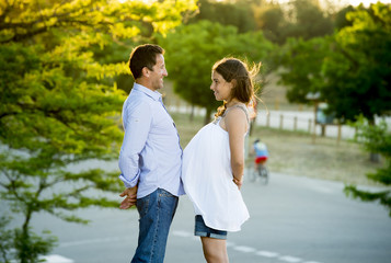 happy couple in love together in park landscape on sunset with woman pregnant belly and man