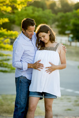 happy couple in love together in park landscape on sunset with woman pregnant belly and man