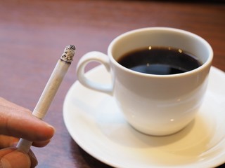 煙草を吸う若い男性の手とコーヒー