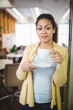 Portrait of young businesswoman having coffee at office
