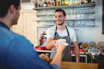 Obraz premium Happy waiter giving coffee to customer at cafe