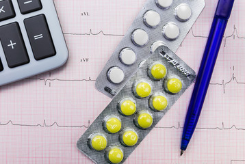 Calculator and pills on the cardiogram background