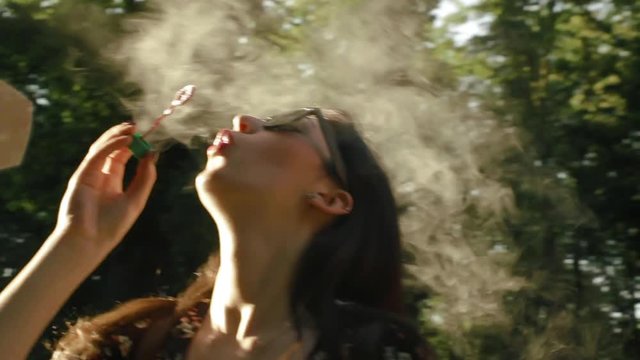 Cute girls having fun smoke e-cigarette and soap bubbles with sunlight