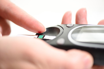 First type Diabetes patient measuring glucose level blood test use glucometer and small drop of blood from finger and test strips