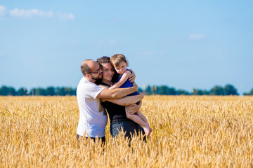Happy smiling family standing on wheat field