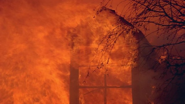 Flames of house fire engulfing gable window