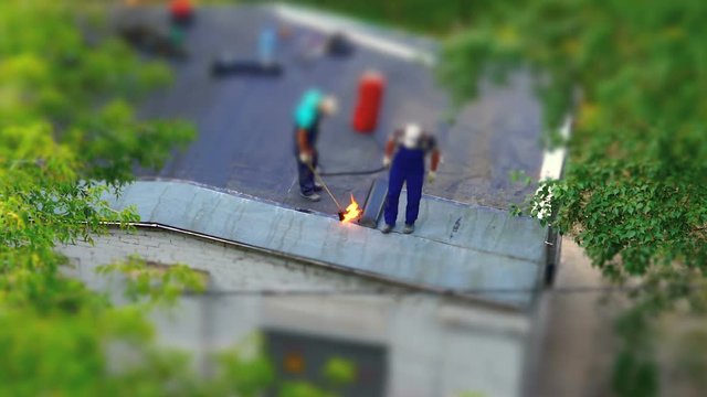 workers heating and melting of bitumen roll during roof repair