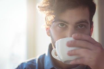 Close-up of young customer drinking coffee at cafe