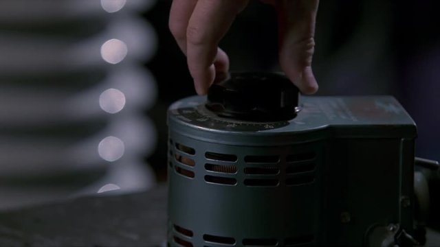 Close-up of hand turning a rheostat up