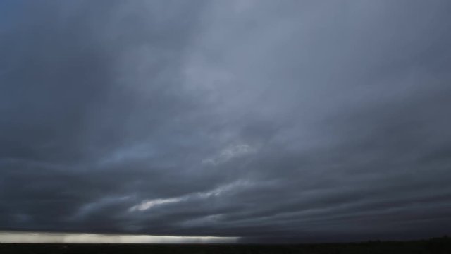Time-lapse gathering thunderstorm clouds above dark plains