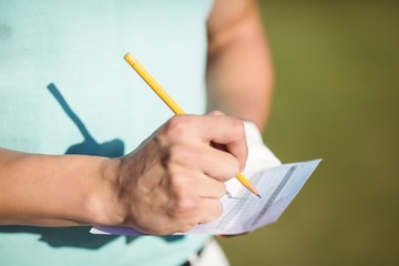 Midsection of golfer with score card