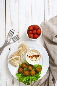 Vegetarian falafels and hummus on white wooden table


