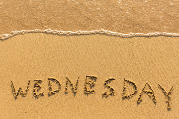 Wednesday - drawn by hand on a sandy golden sea beach.