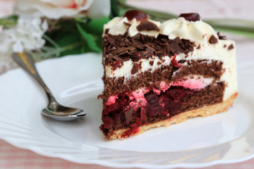 A piece of Black Forest cake on the white plate with flowers
