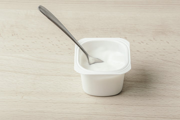 White milk Yogurt with silver spoon on a wooden background