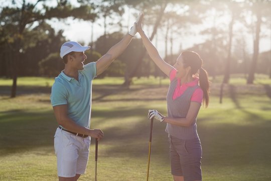 Smiling golf player couple giving high five