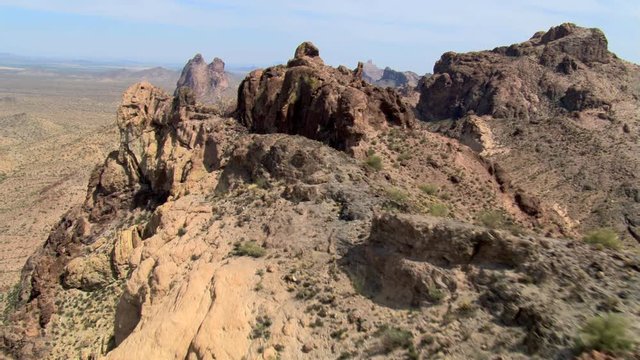 Flight over rugged rocky hills to reveal desert landscape