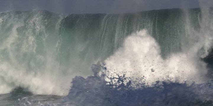 A falling wall of green water exploding in foam and subsiding