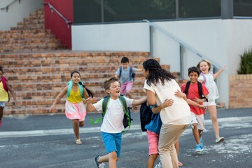 Happy children running towards teacher