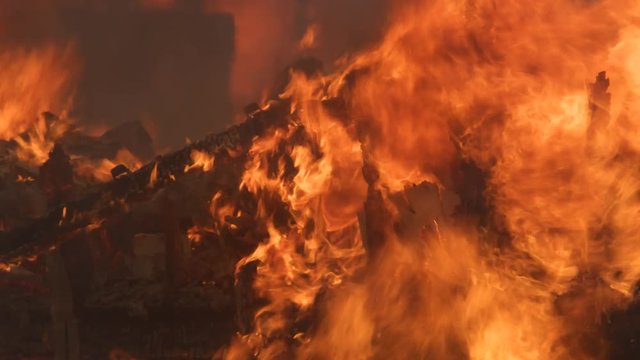 Flames devour the last charred rubble of a house destroyed by fire